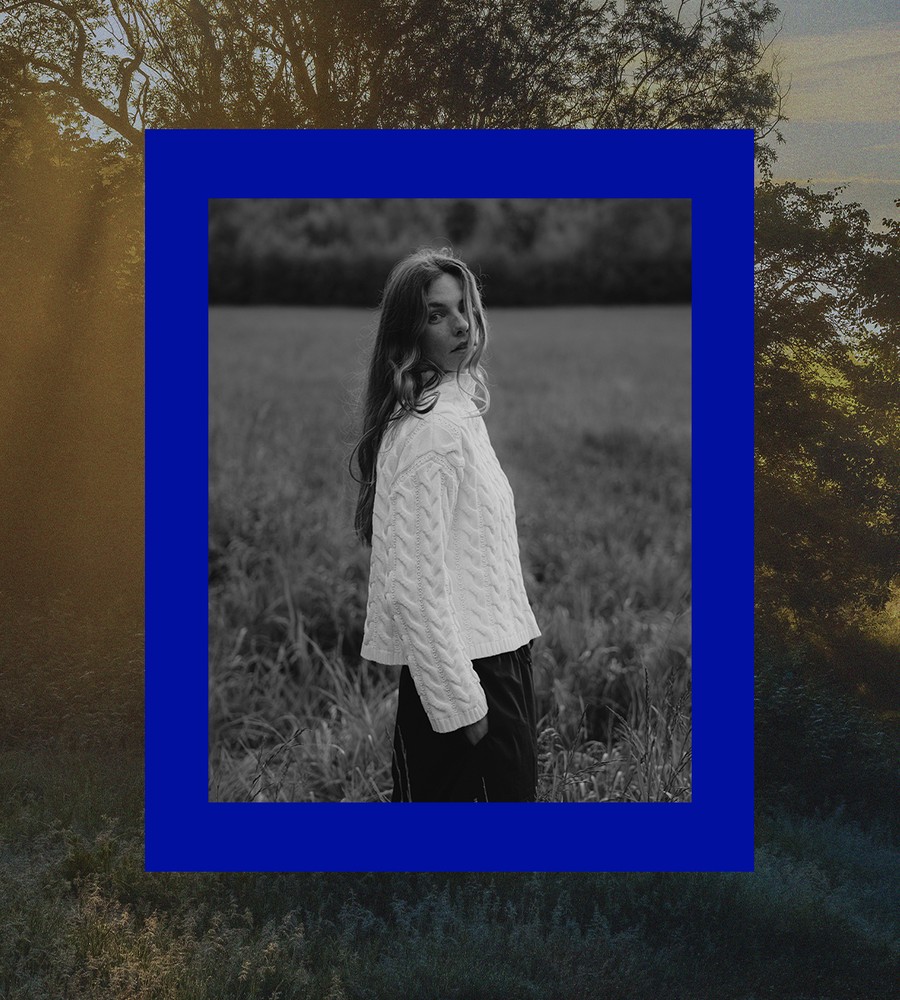 Kvinna går längst med havet i gräset och bär linneplagg