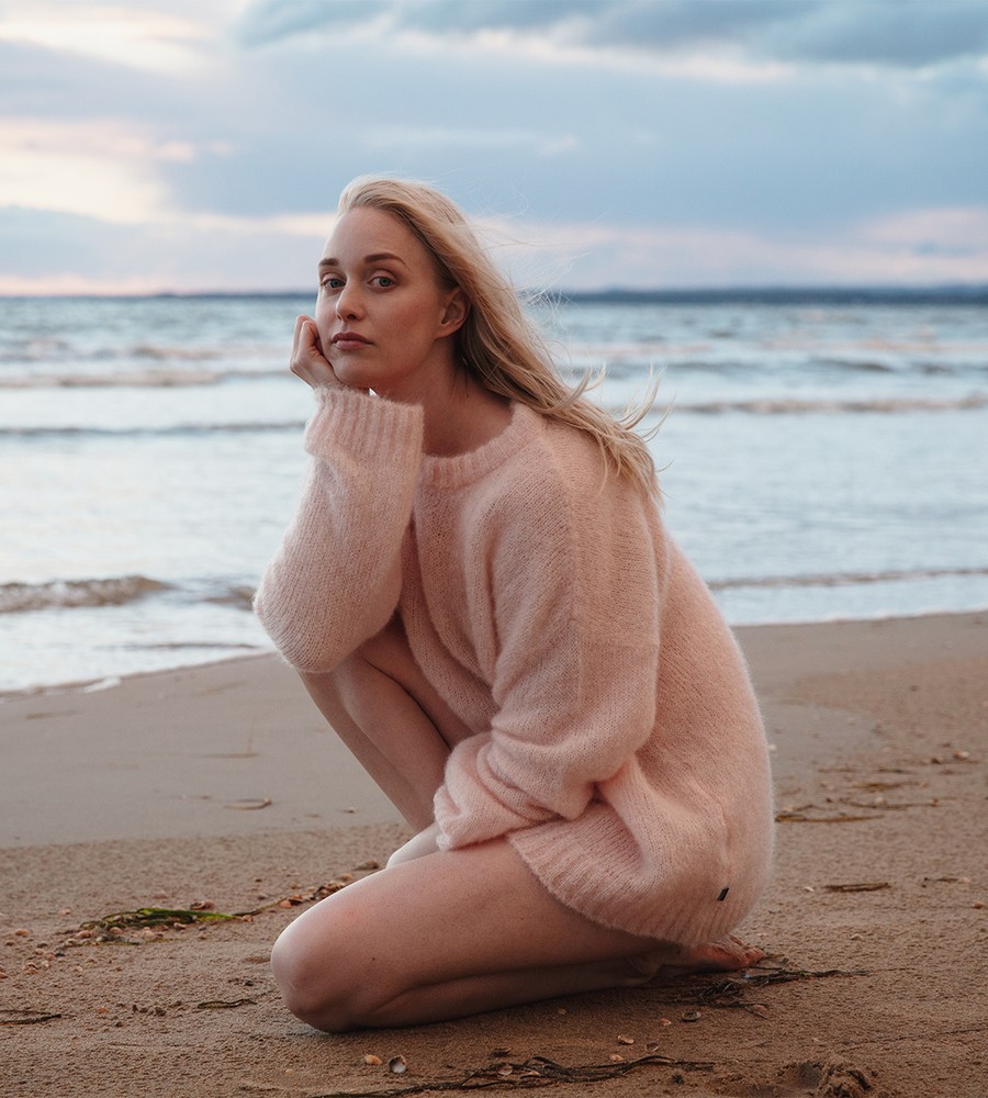 Flera stickade plagg som hänger på galge på en klädställning