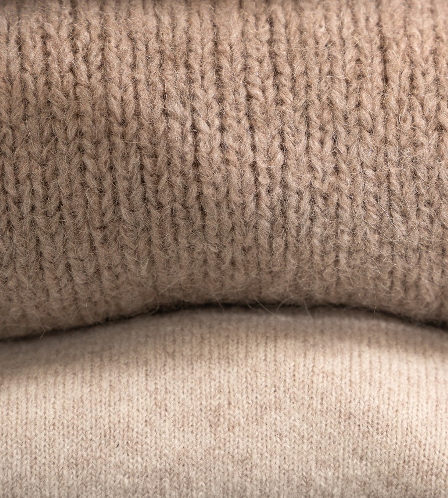 Kvinna och man går längst med strandkanten och bär linneplagg