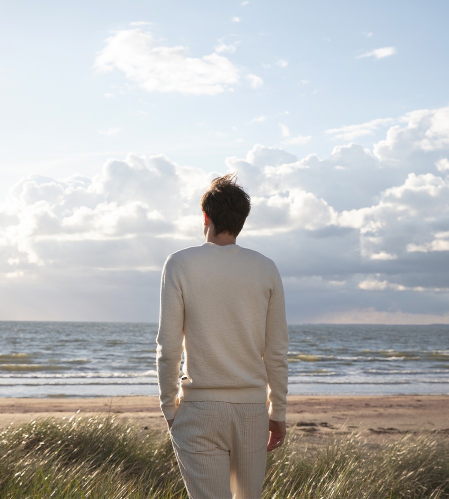 Flera stickade plagg som hänger på galge på en klädställning