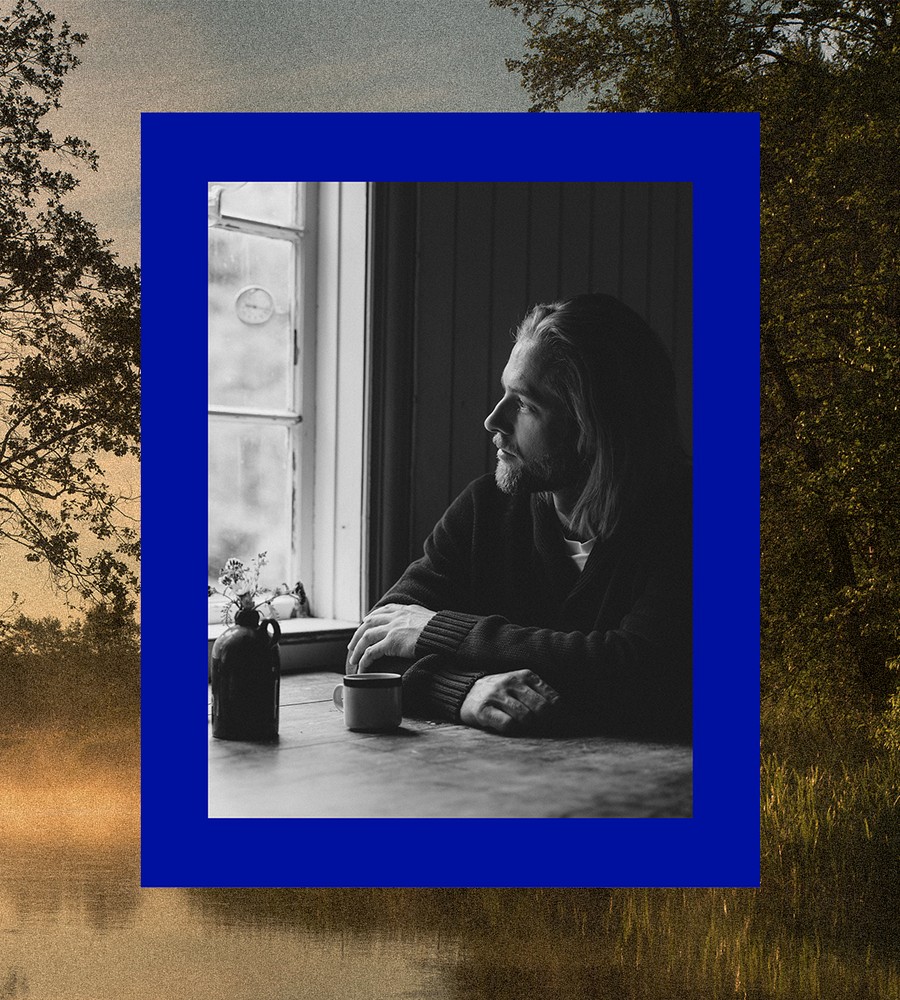 Kvinna går längst med havet i gräset och bär linneplagg