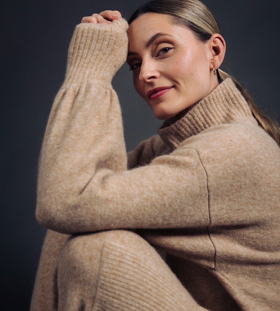 Flera stickade plagg som hänger på galge på en klädställning