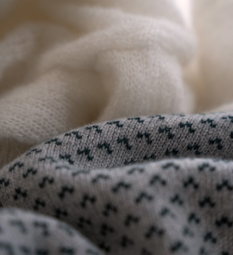 Flera stickade plagg som hänger på galge på en klädställning