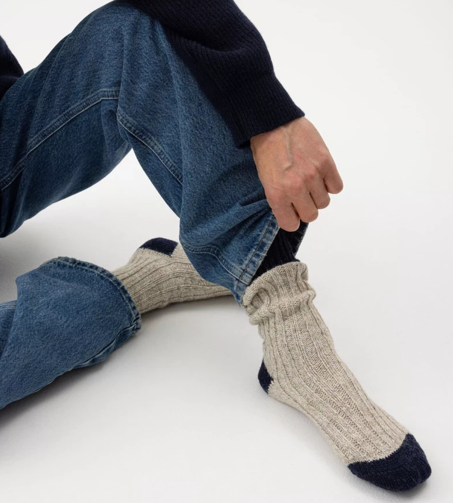 Flera stickade plagg som hänger på galge på en klädställning