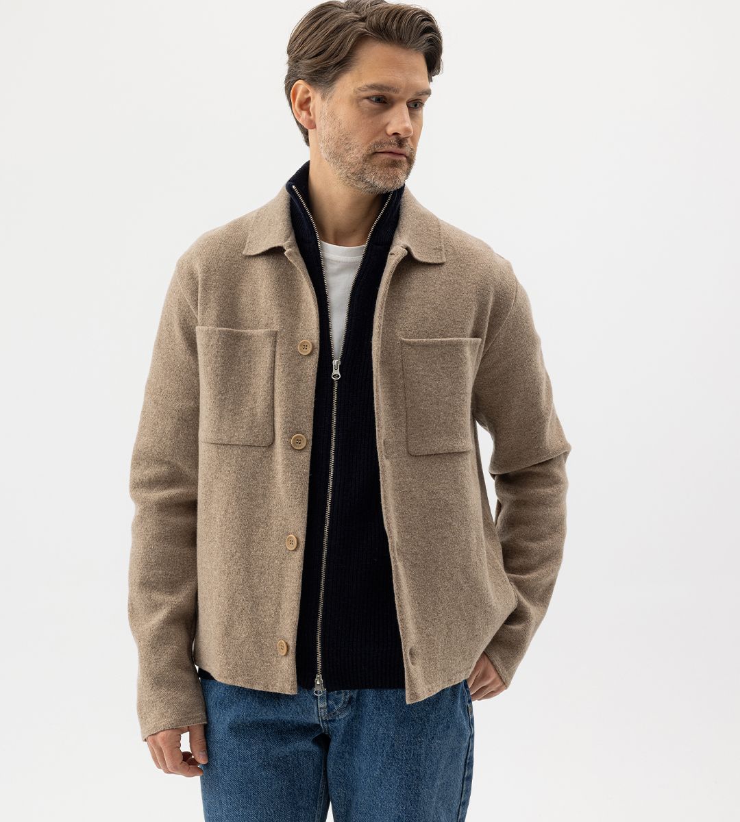 Kille med stickad svart tröja och beige jacka ovan