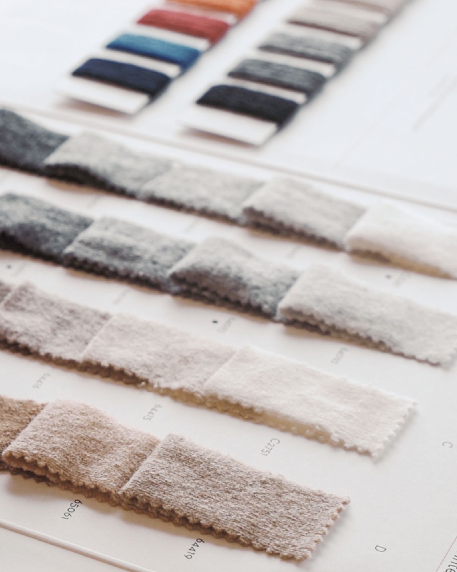 Flera stickade plagg som hänger på galge på en klädställning