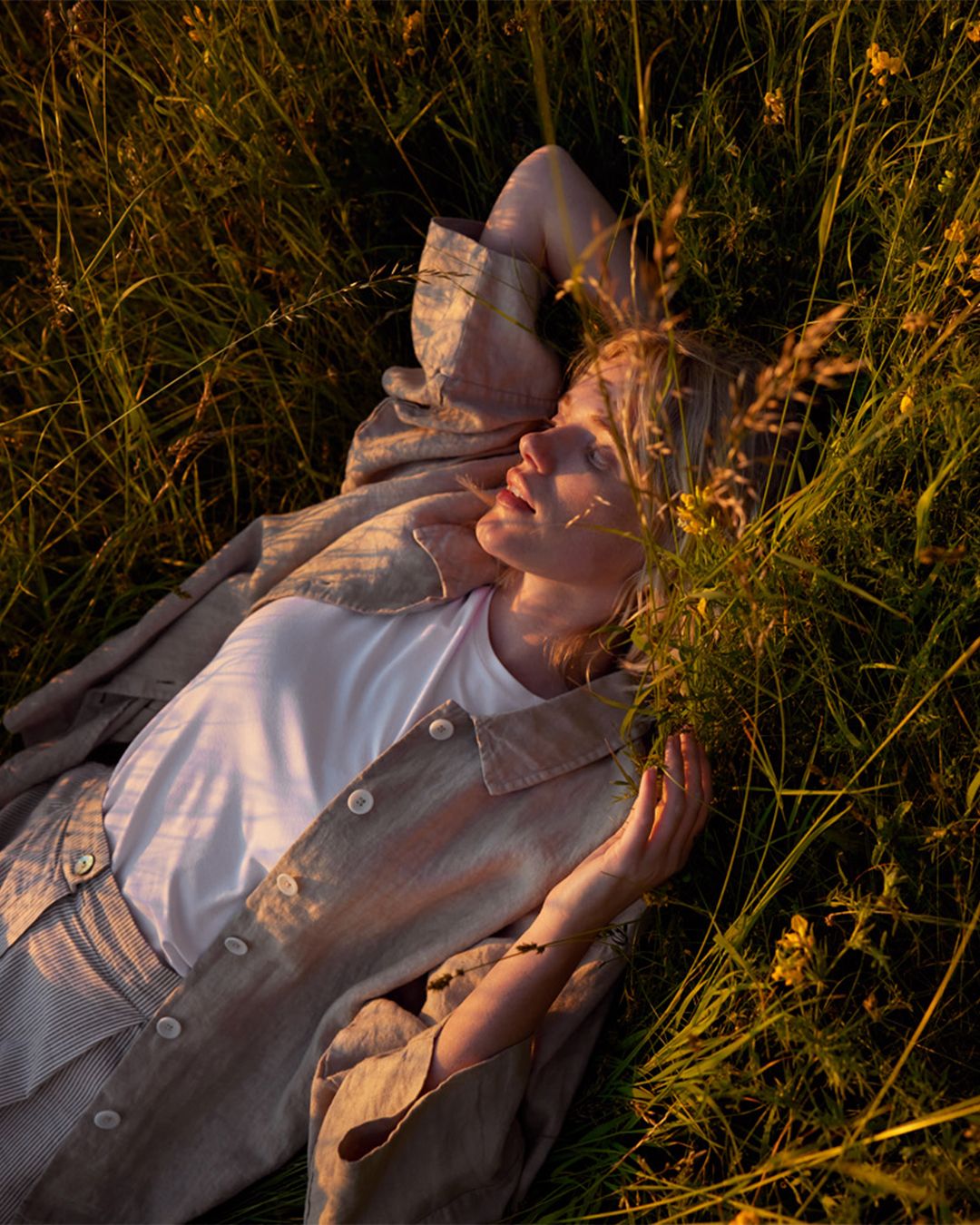 Kvinna ligger i gräset med linneplagg
