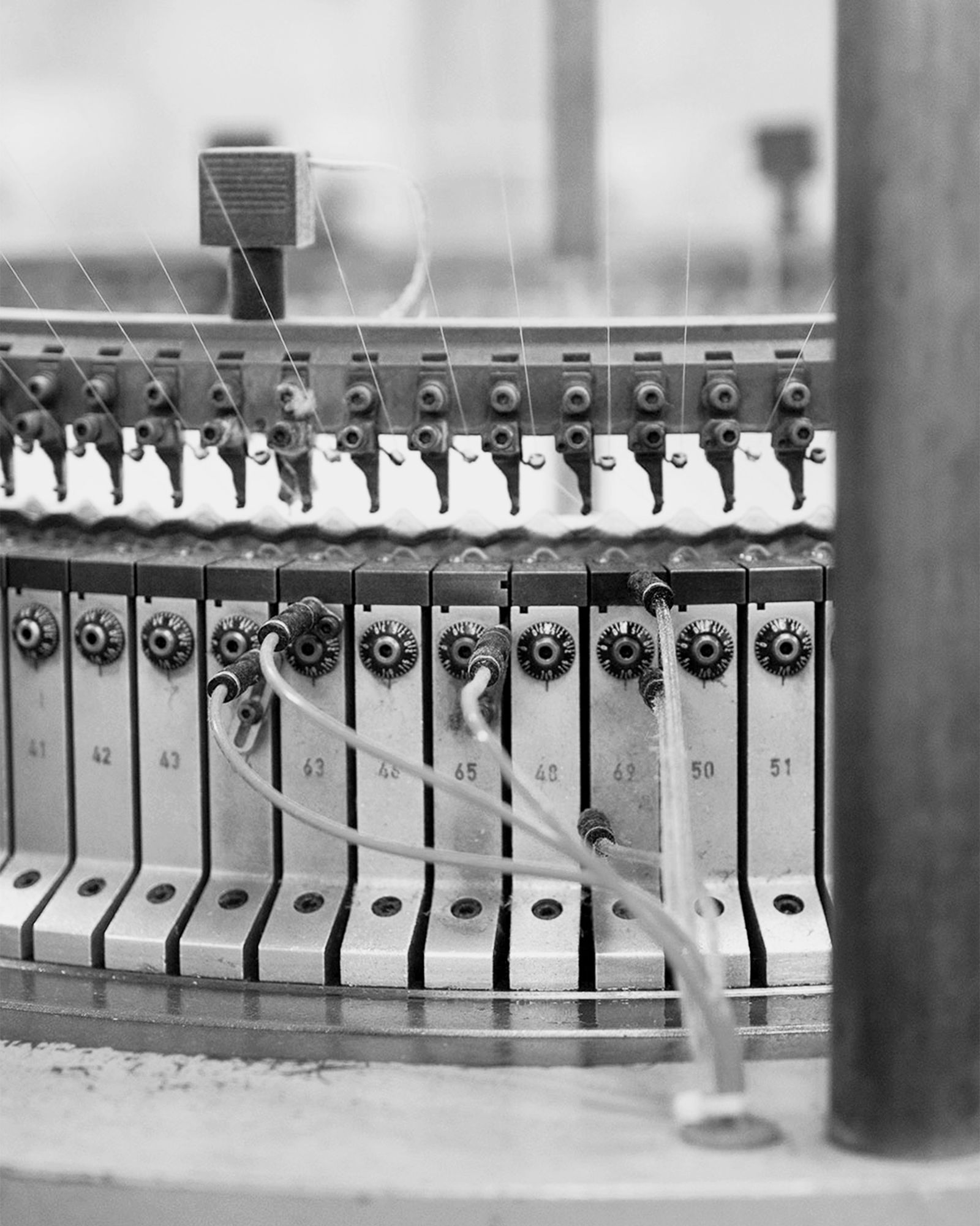 Flera stickade plagg som hänger på galge på en klädställning