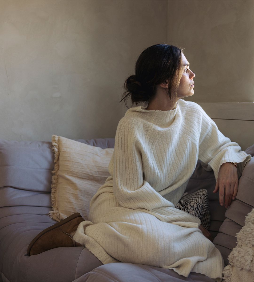 Tjej som sitter i soffa med vit stickad klänning