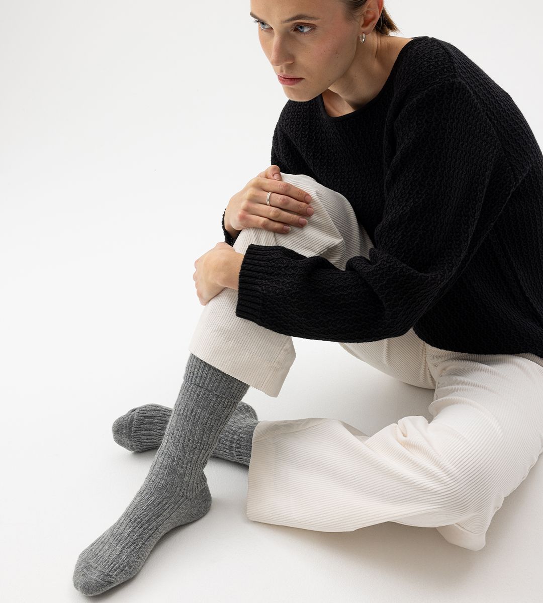 Tjej som sitter ner med stickade raggsockor på sig