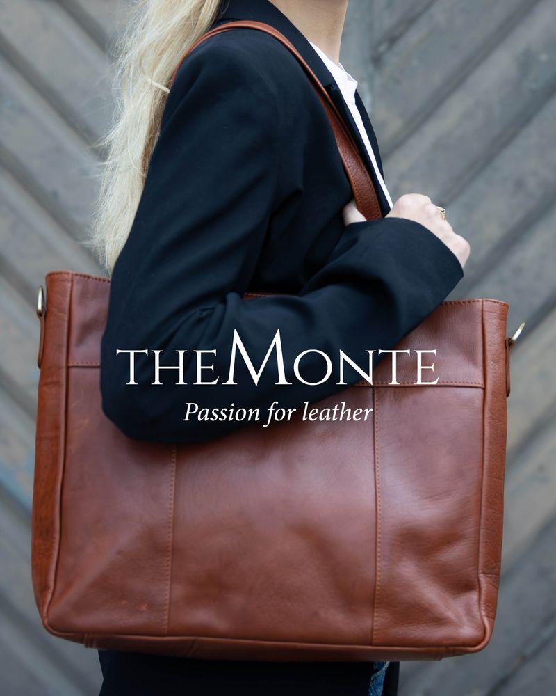 Brun rymlig skinnväska som bärs över axeln av person i kavaj. The monte logo