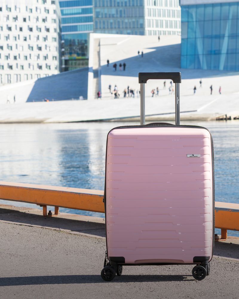 Liten rosa resväska med hjul framför Operahuset i Oslo