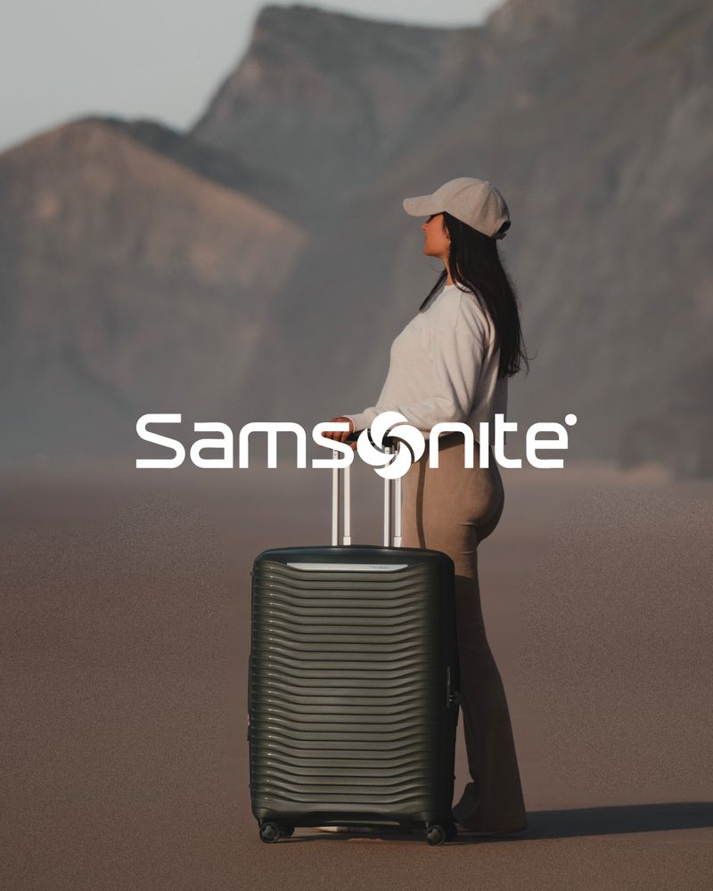Person med svart hård resväska från Samsonite i bergslandskap.