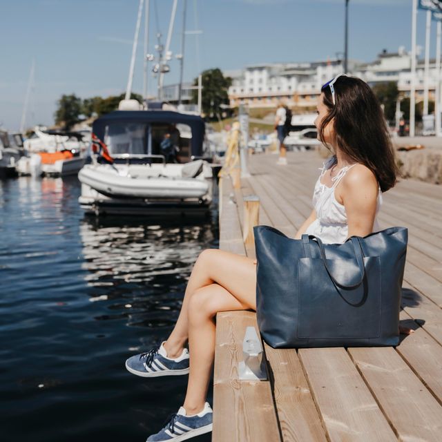 skinntote i navy  fra House of Nordic holdt av dame på brygga ved vannet