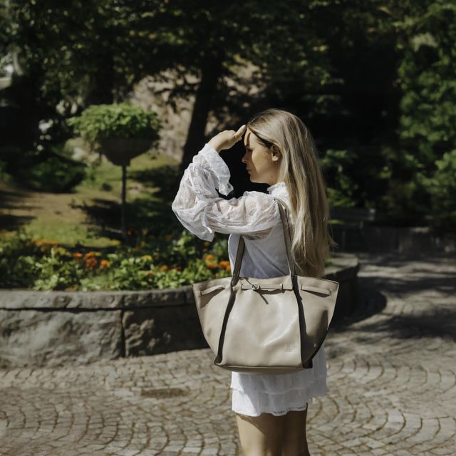 beige tote fra House of Nordic står på parkbenk ved siden av sittende kvinne