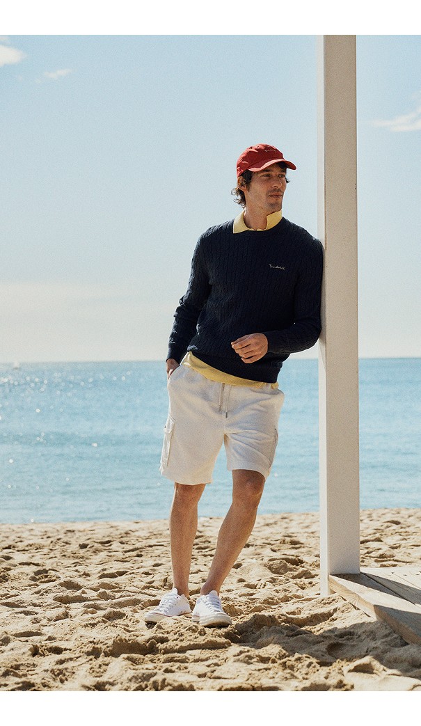 Mand på stranden i strikket trøje fra Bondelid og shorts fra MQ Marqet.