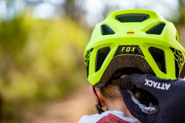 Lapsi takaapäin päässään keltainen Fox Racing pyöräilykypärä.