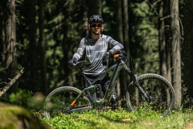 Maastopyöräilijä metsässä edessään Stereo Hybrid 160 täysjousitettu sähkömaastopyörä.