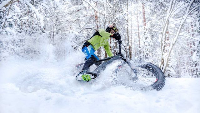 Maastopyöräilijä talvisessa metsässä.