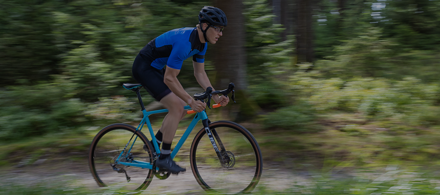 Pyöräilijä ajaa sinisellä Cube cyclocross-pyörällä metsässä.