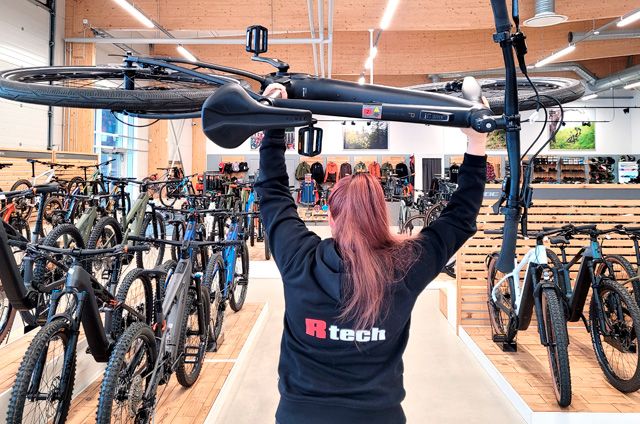 Rtechin työntekijä kannattelee myymälässä polkupyörää pään yläpuolella.