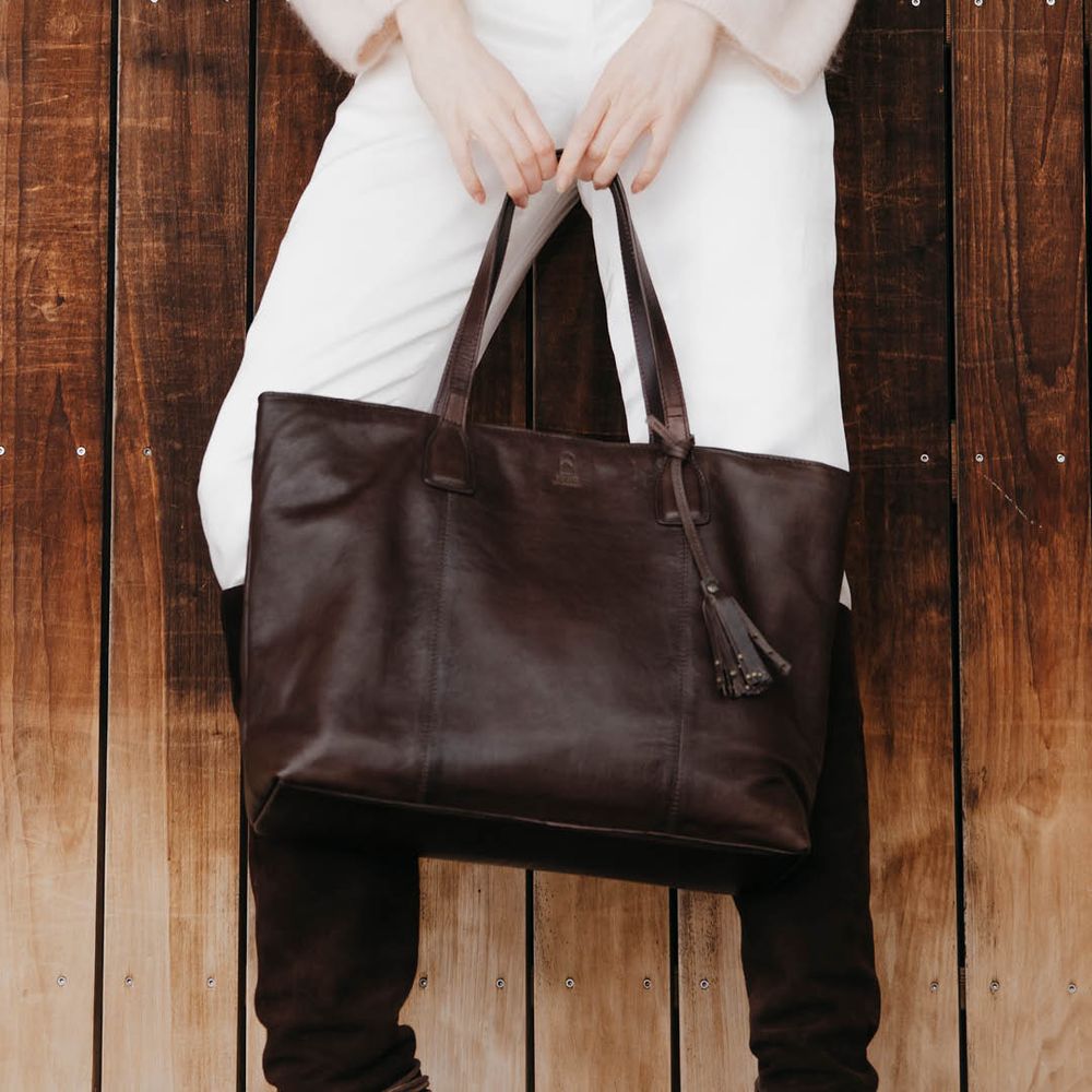 Stor brun totebag i skinn holdt av person