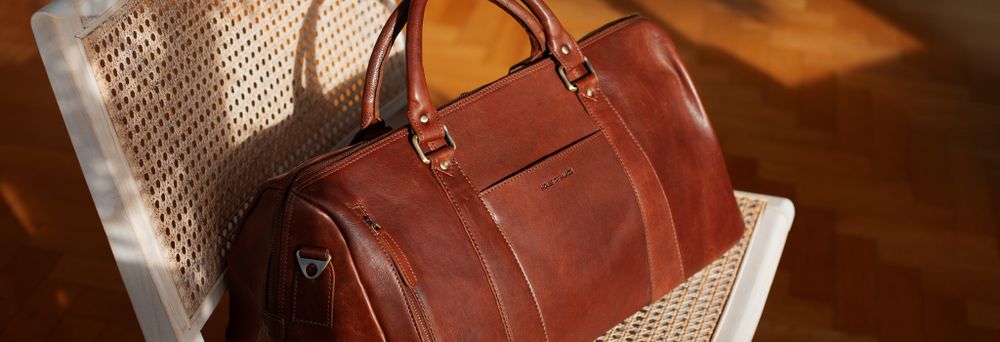 Brun weekendbag i skinn på rotting loungestol